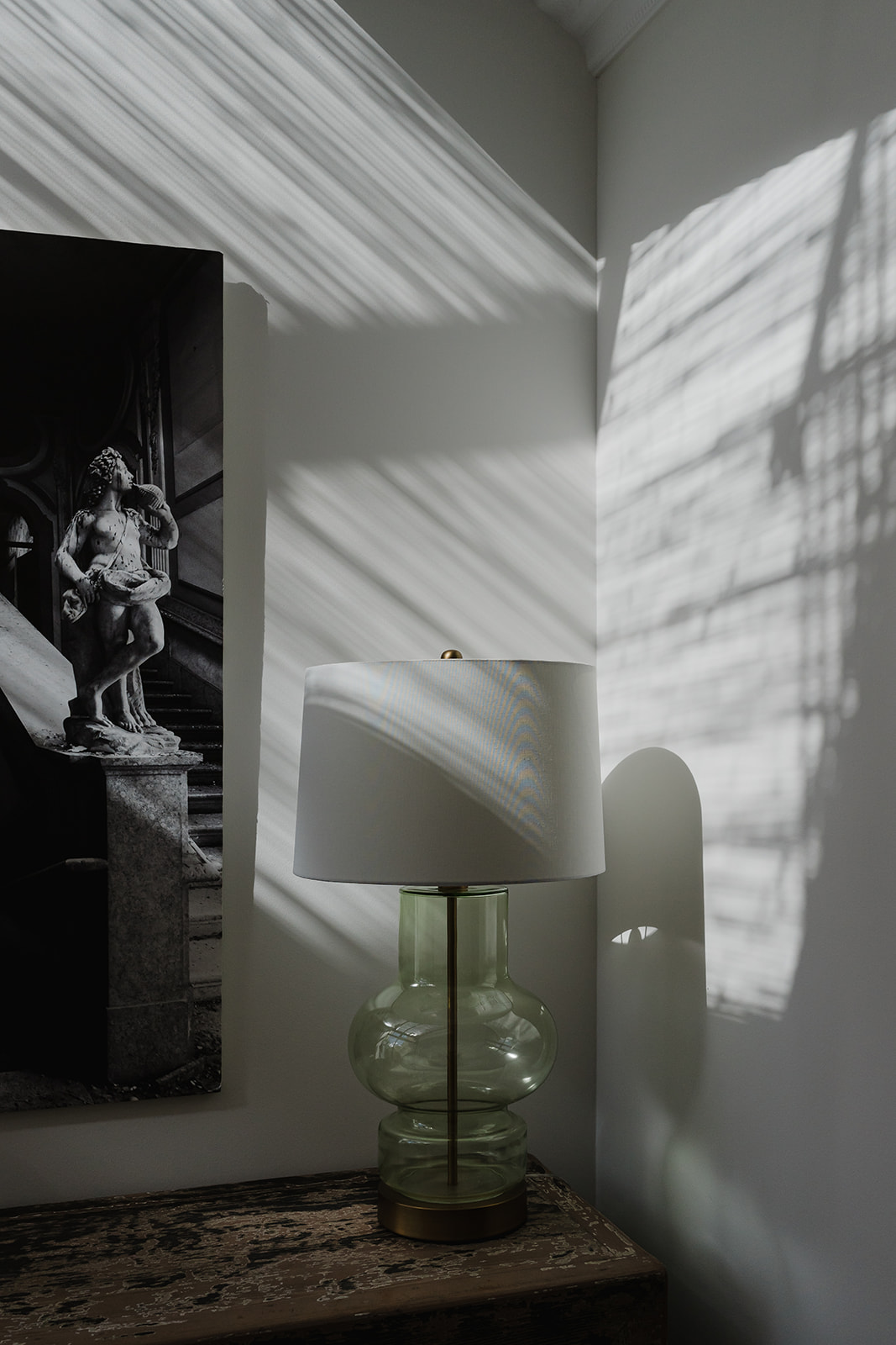 Lámpara de mesa sobre mesita de piedra con sombras naturales en un interior mediterráneo.