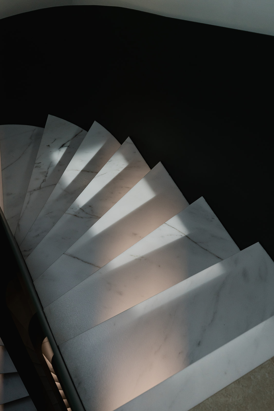 Diseño de escalera en mármol y barandilla de metal curva - Vilaplana Studio